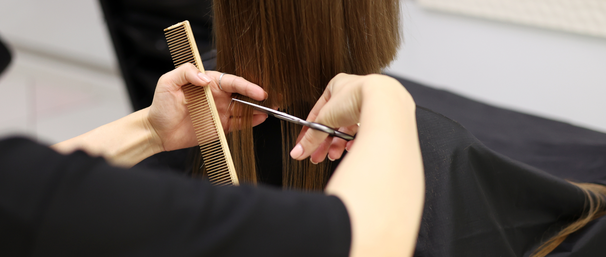 Kapster knipt het haar van een cli&euml;nt in de salon